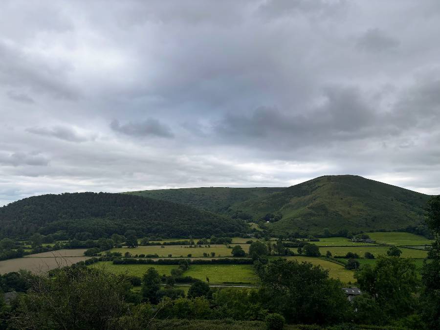 Green hills and fields with a dark cloudy sky above